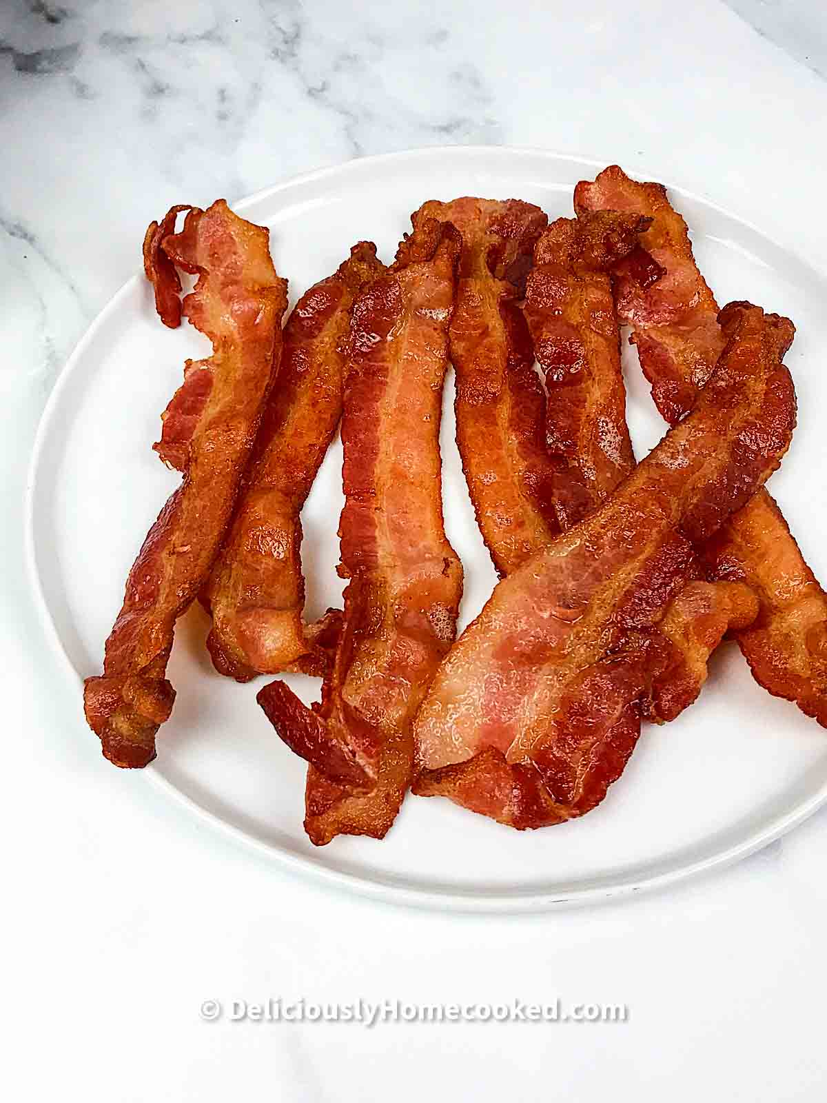 Air fried bacon slices on a white plate 